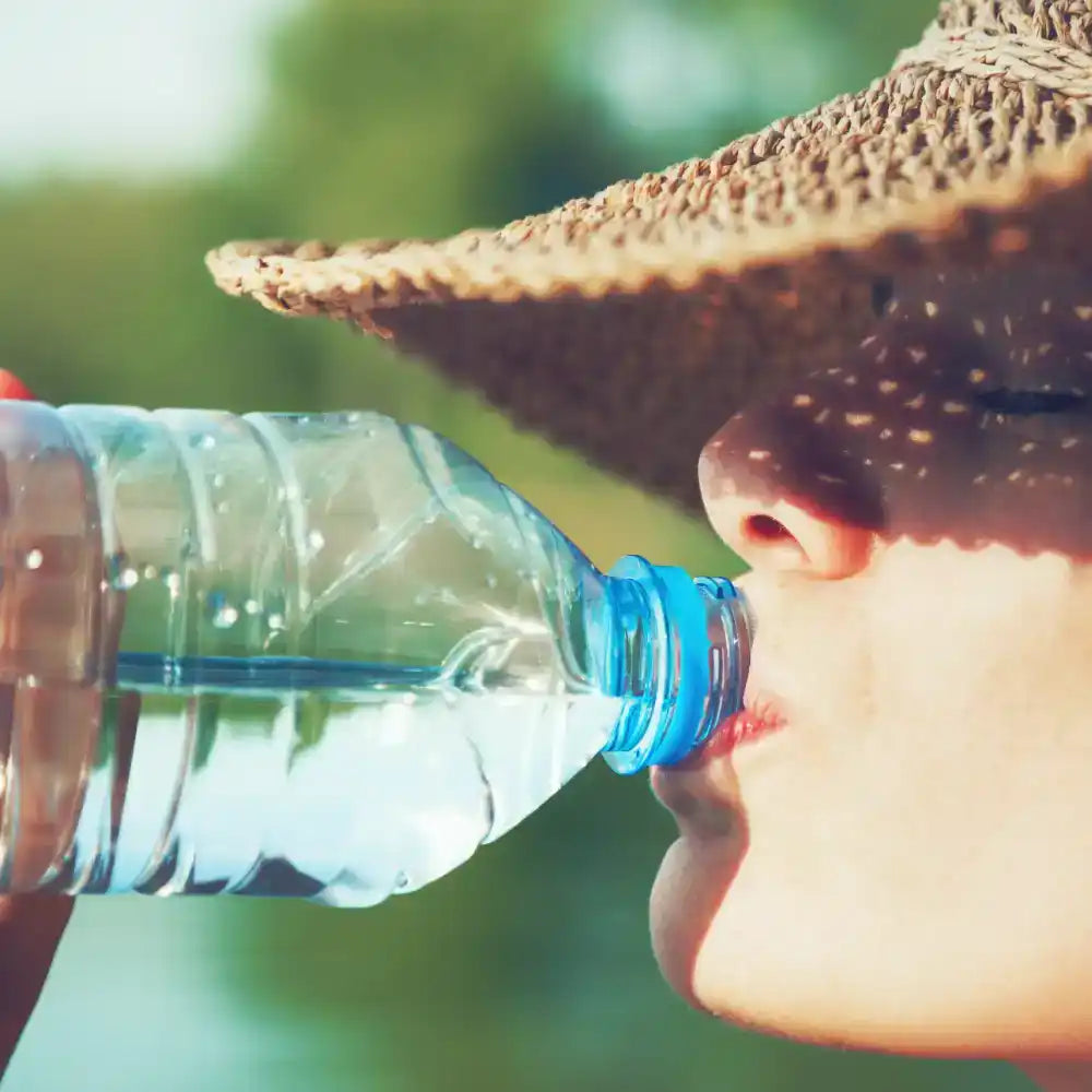 A person drinking water from a plastic bottle.